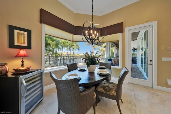 Dining area with plenty of natural light, beverage cooler, a notable chandelier, and ornamental molding