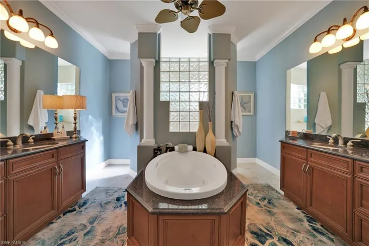 Bathroom with ornamental molding, a tub to relax in, and decorative columns