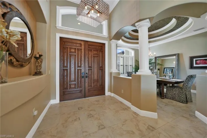 Entrance foyer featuring decorative columns, ornamental molding, a towering ceiling, and an inviting chandelier