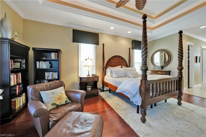 Bedroom with ornamental molding, a raised ceiling, and dark wood-type flooring