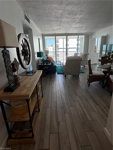 Living room with healthy amount of natural light, dark wood finished floors, a textured ceiling, and expansive windows