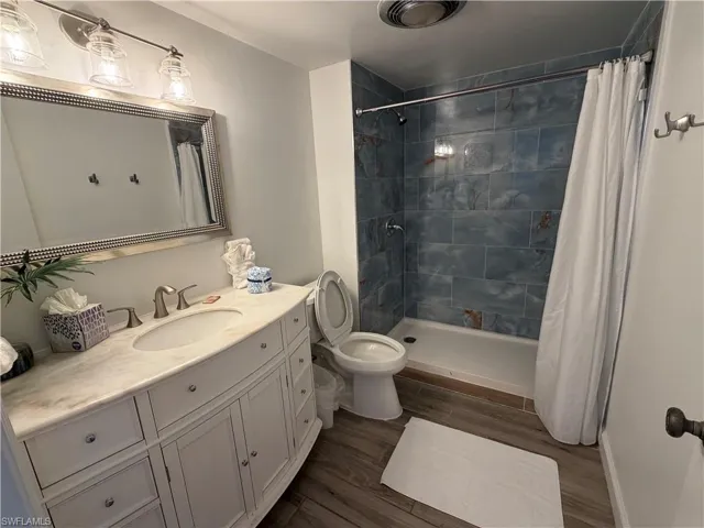 Full bathroom featuring a stall shower, vanity, and dark wood finished floors