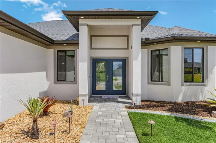 Entrance to property featuring stucco siding, a shingled roof, and french doors