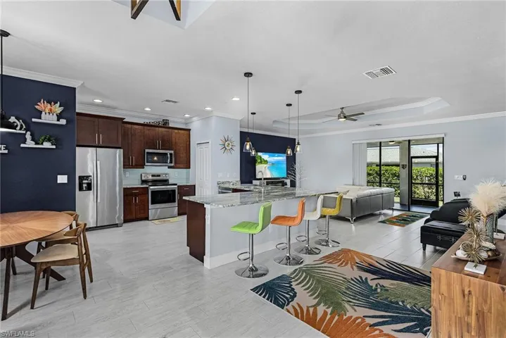 Kitchen featuring visible vents, crown molding, a kitchen bar, appliances with stainless steel finishes, and ceiling fan