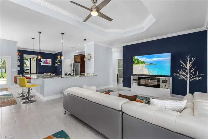 Living room with ceiling fan, baseboards, crown molding, and a tray ceiling
