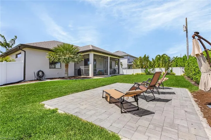 Back of property with a fenced backyard, stucco siding, a patio, a lawn, and a sunroom