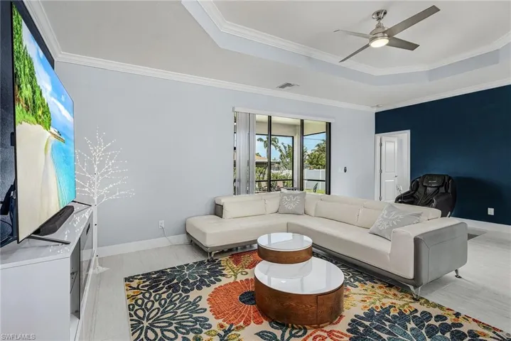Living room featuring ceiling fan, crown molding, visible vents, and a raised ceiling