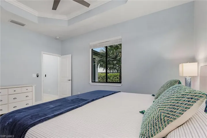 Bedroom featuring ornamental molding, a ceiling fan, visible vents, and a raised ceiling