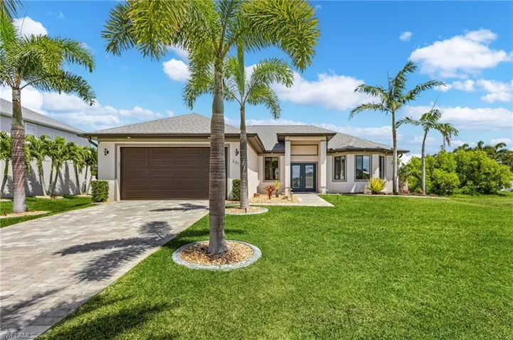 View of front of home with stucco siding, french doors, decorative driveway, a front yard, and a garage