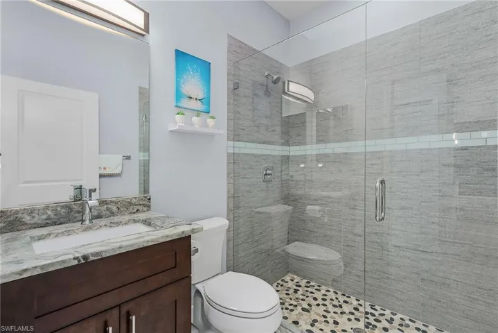 Bathroom featuring a shower stall, toilet, and vanity