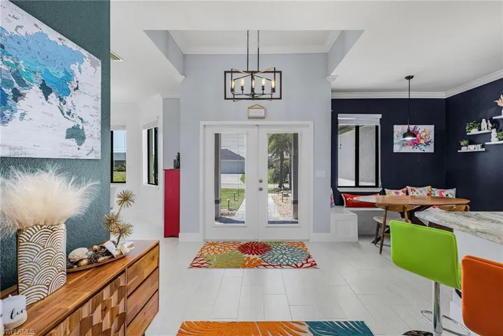 Entryway with baseboards, a notable chandelier, french doors, and crown molding
