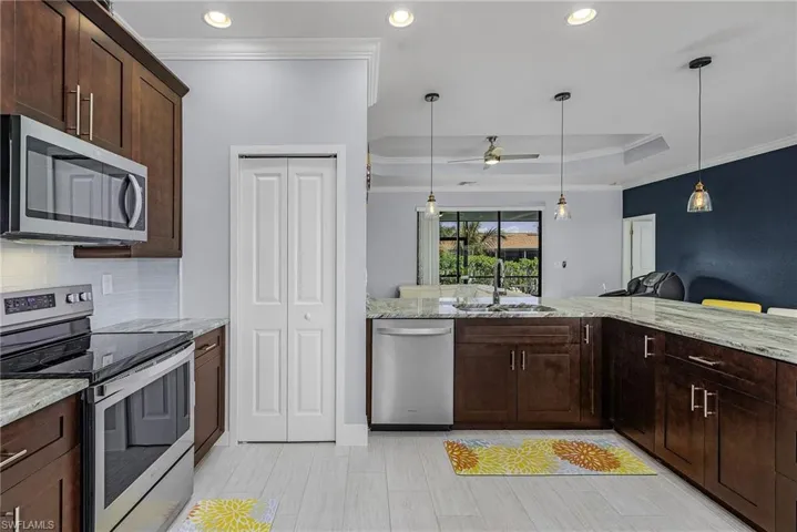 Kitchen featuring appliances with stainless steel finishes, a ceiling fan, ornamental molding, and a sink
