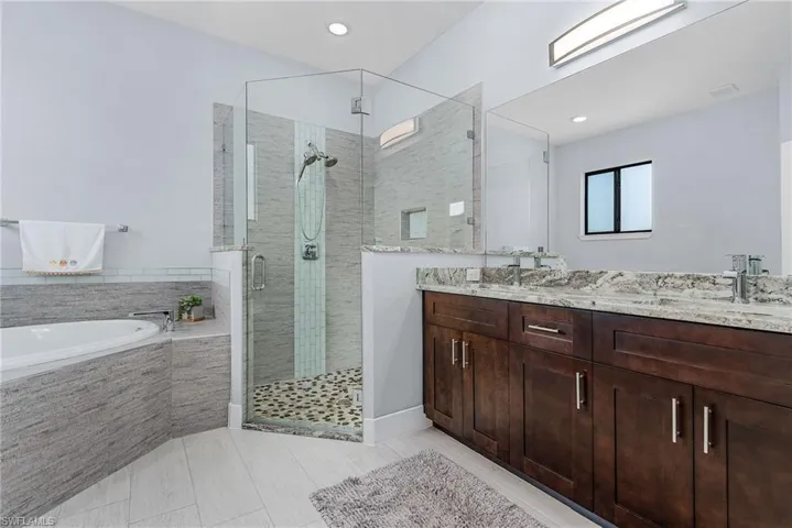 Bathroom with a shower stall, tile patterned flooring, double vanity, a sink, and a garden tub