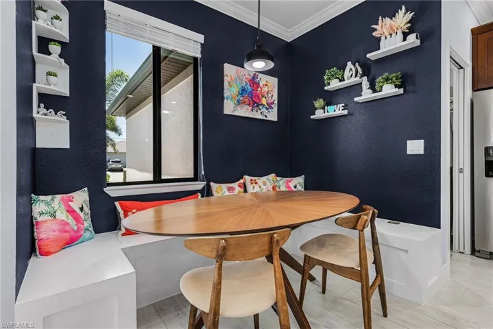 Dining area featuring a textured wall, light wood-style floors, breakfast area, and ornamental molding