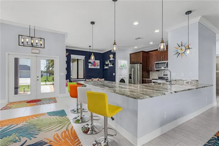 Kitchen with stainless steel appliances, a kitchen bar, a notable chandelier, and crown molding