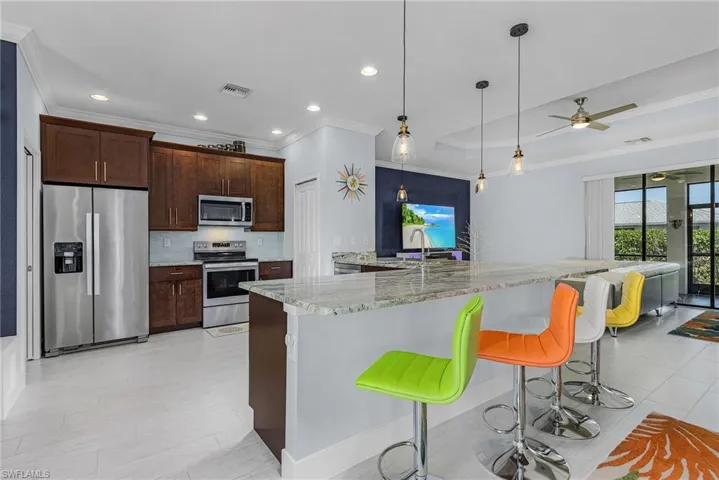 Kitchen with light stone countertops, visible vents, appliances with stainless steel finishes, and crown molding