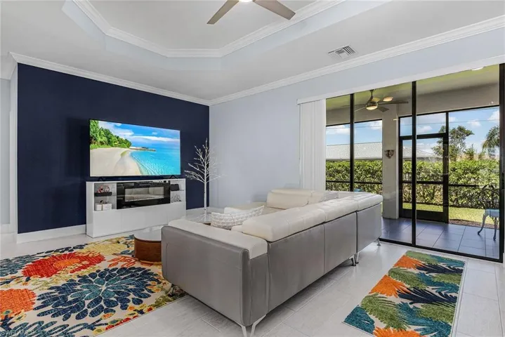 Living room with visible vents, a raised ceiling, ceiling fan, and crown molding