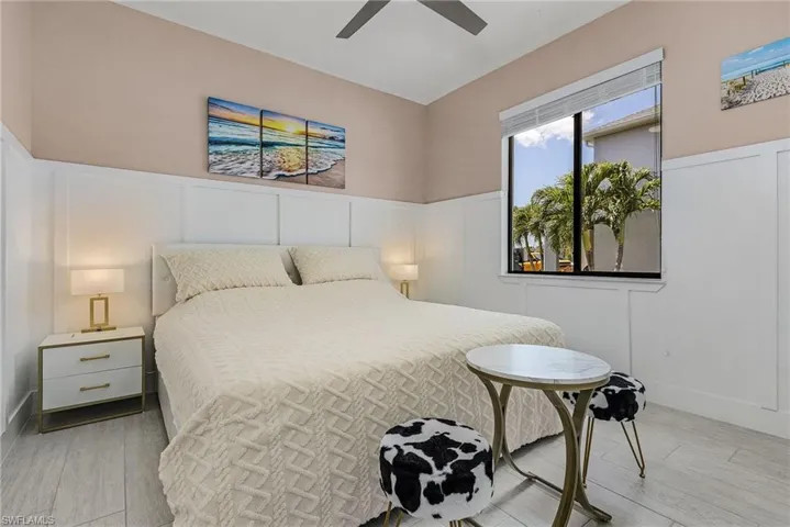 Bedroom with wainscoting, a ceiling fan, wood finished floors, and a decorative wall