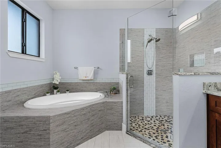 Bathroom with a garden tub, vanity, and a stall shower