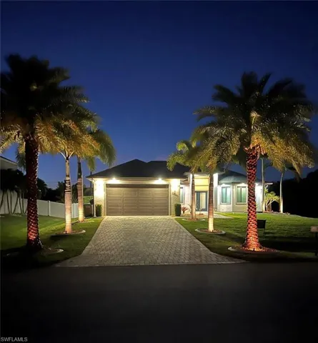 View of front of house with a lawn, fence, decorative driveway, and a garage