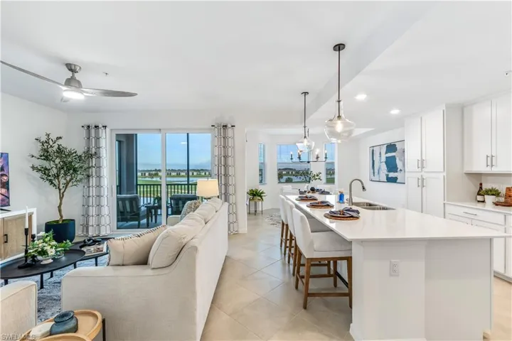 Kitchen featuring white cabinetry, pendant lighting, an island with sink, sink, and a breakfast bar