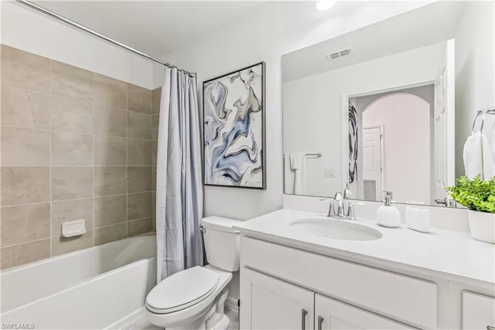 Full bathroom featuring shower / bathtub combination with curtain, toilet, and large vanity