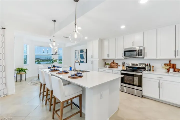 Kitchen with white cabinets, stainless steel appliances, a kitchen island with sink, and sink
