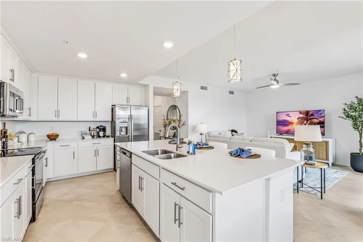 Kitchen featuring appliances with stainless steel finishes, white cabinetry, ceiling fan, and a kitchen island with sink