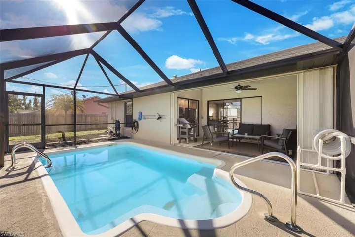 View of pool featuring ceiling fan, glass enclosure, and a patio