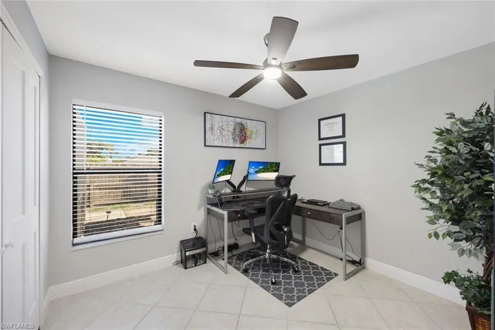 Home office with ceiling fan and light tile floors