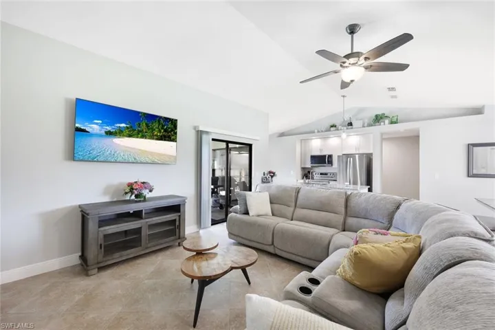 Living room with high vaulted ceiling, ceiling fan, and light tile flooring