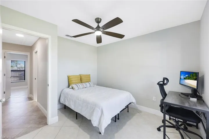Bedroom with ceiling fan and light tile flooring