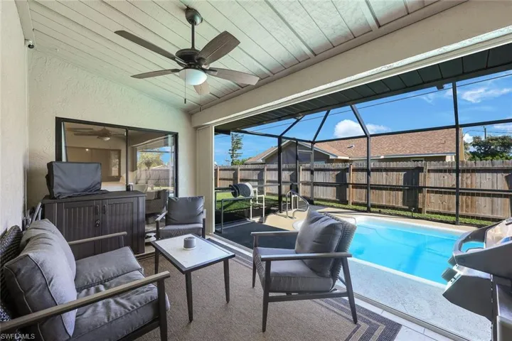 View of pool featuring ceiling fan, an outdoor living space, glass enclosure, and a patio area