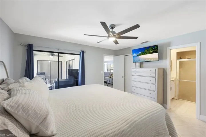 Tiled bedroom featuring ceiling fan, connected bathroom, and access to exterior
