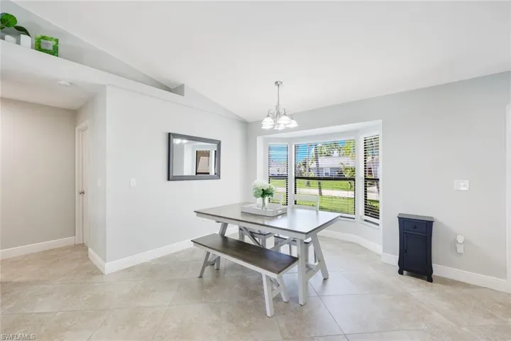 Dining area featuring a notable chandelier, lofted ceiling, and light tile floors