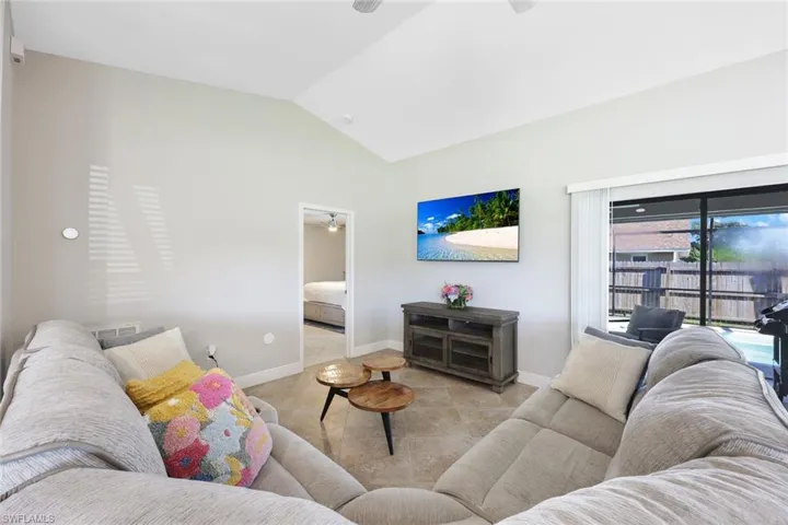 Tiled living room with vaulted ceiling and ceiling fan