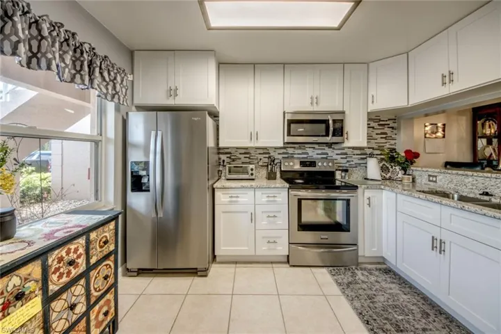 Kitchen featuring white cabinets, tasteful backsplash, appliances with stainless steel finishes, and a new light fixture has dimmer feature