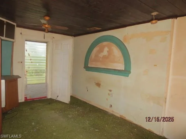 Carpeted spare room featuring wooden ceiling and ceiling fan