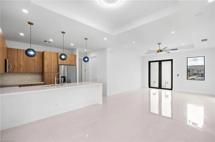 Kitchen featuring brown cabinetry, modern cabinets, open floor plan, recessed lighting, and appliances with stainless steel finishes