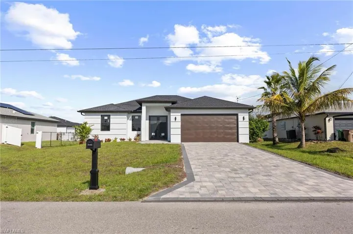 Prairie-style house featuring decorative driveway, a garage, roof with shingles, and stucco siding