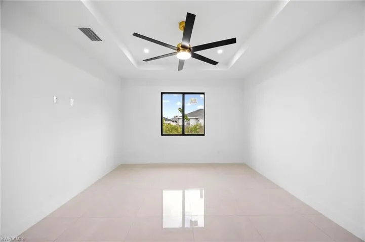 Empty room featuring a tray ceiling, light tile patterned floors, and recessed lighting