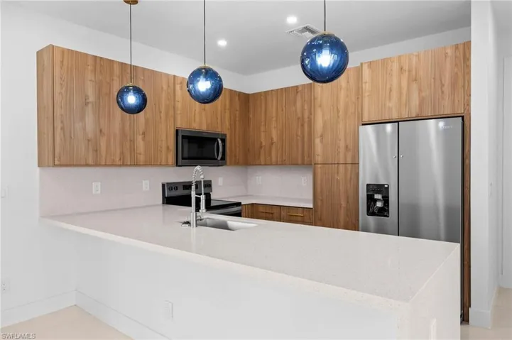 Kitchen with light stone counters, a peninsula, modern cabinets, pendant lighting, and recessed lighting