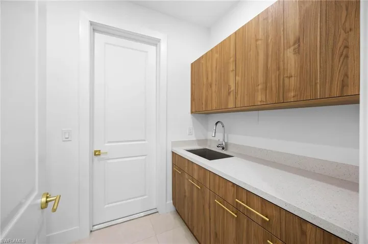 Bar featuring brown cabinets, light stone counters, modern cabinets, and light tile patterned floors
