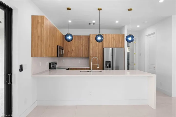 Kitchen featuring a peninsula, decorative light fixtures, modern cabinets, appliances with stainless steel finishes, and recessed lighting