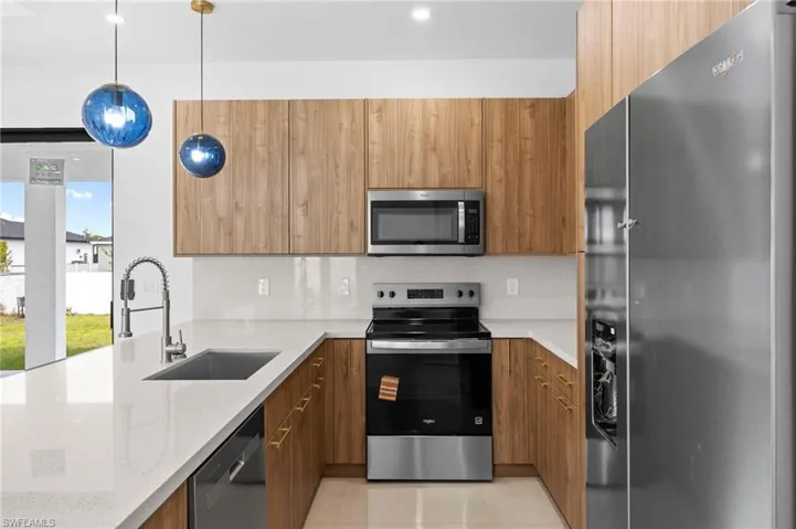 Kitchen with stainless steel appliances, modern cabinets, hanging light fixtures, light stone countertops, and recessed lighting