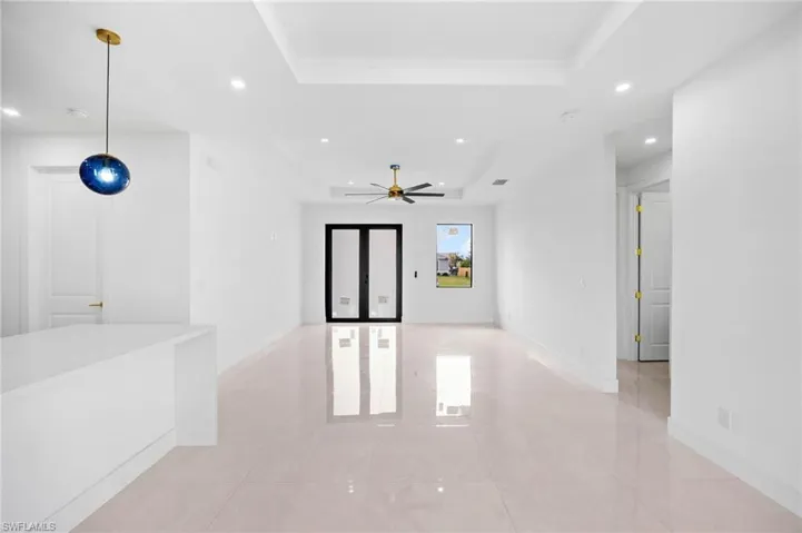 Empty room featuring a raised ceiling, recessed lighting, light tile patterned floors, and ceiling fan