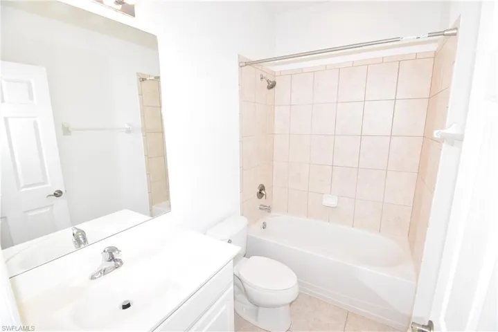 Bathroom featuring vanity, bathing tub / shower combination, and light tile patterned flooring