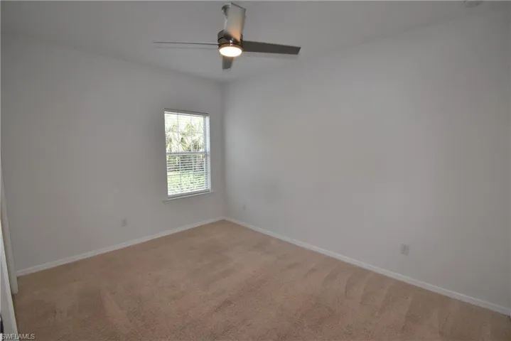 Empty room with light carpet and a ceiling fan