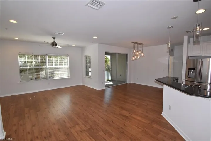 Unfurnished living room with dark wood-type flooring, recessed lighting, ceiling fan, and a chandelier