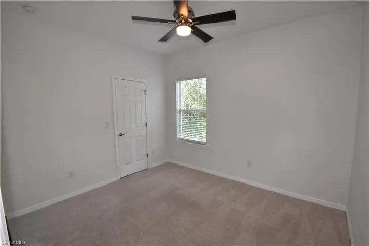 Carpeted empty room featuring baseboards and ceiling fan